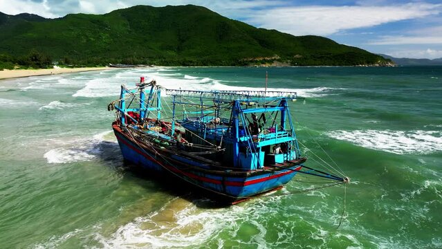 Fishing boat with a big catch of fish stranded with a catch, aerial view, drone, sunset, summer. A small fishing ship that was stranded due to a strong storm. Seagulls. Bright Disk of Sun.
