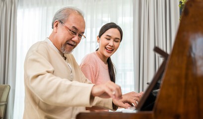 Family. Young woman teaching piano for senior man teaching, happy daughter and elderly father with...
