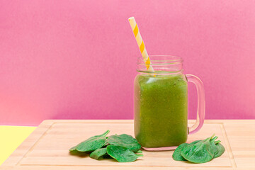 Fresh Green Smoothie of Apple, Celery, and Spinach in Glass Smoothie Jar with Yellow Cocktail Straw on Wooden Cutting Board. Vegan Detox Drink. Vegetarian Culture. Healthy Eating and Fruit Diet