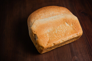 A loaf of bread on a wooden brown background.