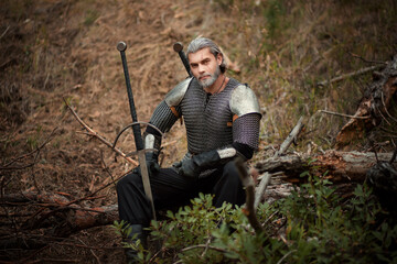 An aged male warrior in chain mail with gray hair and a scar on his face. Knight in armor holds a...