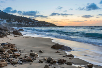 Stunning landscape image of Sennen Cove in Cornwall during sunset with dramatic sky and long exposure sea motion