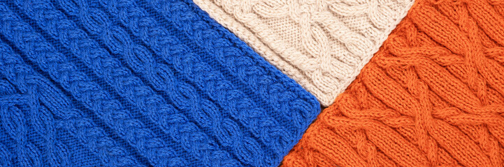 Fototapeta na wymiar Knitted blue orange and beige background. Large knitted fabric with a pattern. Close-up of a knitted blanket. Banner