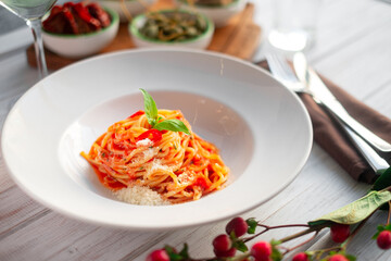 Spaghetti in tomato sauce with basil and parmesan in a white plate. Italian pasta recipe with tomatoes, close up