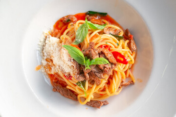 Spaghetti pasta with tomato sauce and beef stew, tomatoes, parmesan cheese and fresh basil on a wooden background. Italian cuisine, top view