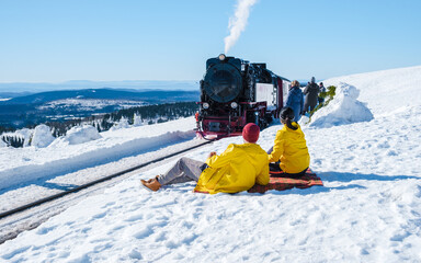 a couple of men and women watching the steam train on the way to Brocken through the winter landscape, Brocken, Harz national park Germany