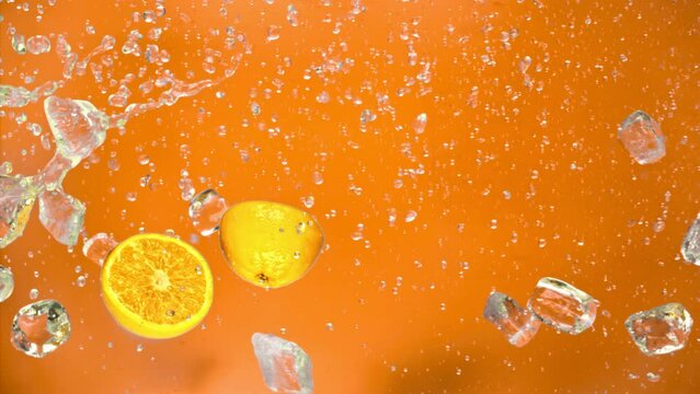 Juicy tasty sweet bright vibrant orange fly along on ice and water splashes drops in super slow motion. Cool rich juicy citrus cold oranges slices falling or exploding on orange background on 1000 fps