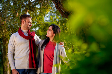 Indian couple wearing colourful warm sweater or woolen winter cloths and walking at garden