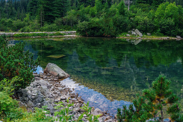 Beautiful summer landscape of High Tatras, Slovakia - Poprad lake, lush forest, reflecting on water surface, mountains