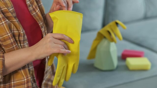 unrecognizable woman is tired of cleaning the house, angrily takes off and throws away rubber yellow gloves.