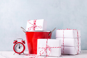 Composition with  wrapped boxes with presents in red bucket and red clock against  blue textured  wall. Scandinavian style. Place for text.