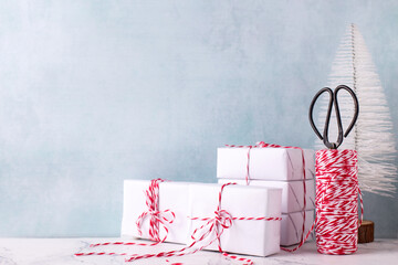 Card with  wrapped boxes with presents, bikers twine, scissors and white tree against  blue textured  wall. Scandinavian style. Place for text.