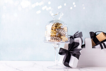 New Year  postcard. Golden and silver cones decorations and wrapped box with present  on white marble background against blue  textured wall. Selective focus. Place for text. - 554425740