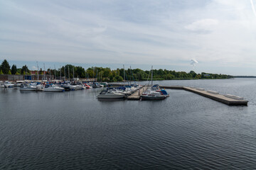Fototapeta na wymiar Big Lake Sentenberg. City harbour. Blue sky. Calm water. Lots of boats and yachts at the pier. A beautiful place to relax in nature near the water. Germany. . Without people