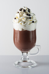 Glass cup with handle containing chocolate, whipped cream and chocolate balls.