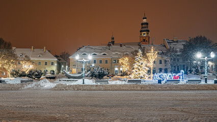 Rynek starego miasta zimą w nocy, Wodzisław Śląski w Polsce zasypany śniegiem z choinkami i światełkami świątecznymi 