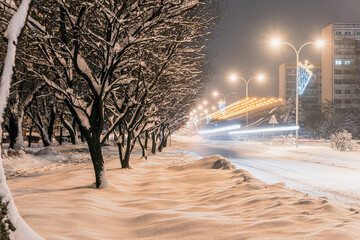 Mocno zasypane śniegiem droga i chodnik w mieście przemysłowym na Śląsku w Polsce, Jastrzębie-Zdrój nocą.