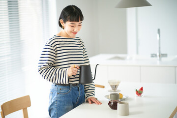 部屋でコーヒーを淹れる若い女性