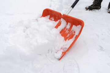Removing snow from the sidewalk on a cold winter day. Snow shoveling, removal after snowstorm. Snow clearing with a shovel.