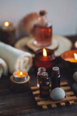 Concept of natural essential organic oils, Bali spa, beauty treatment, relax time. Atmosphere of relaxation, pleasure. Candles, towels, dark wooden background. Alternative oriental medicine