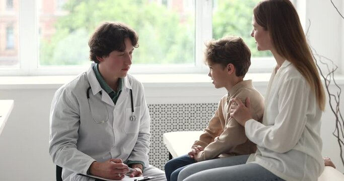 Man paediatrician in white coat gives high five to little boy patient, finish professional medical consultation in clinic, encourages, congratulates with good health checkup result. Medicare, recovery