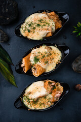 Pancakes with ham, chicken, minced meat, pineapple, onion and cheese sauce in a cast-iron bowls.