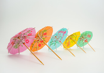 perspective view of a row of cocktail parasol umbrellas isolated against a white background © Cliff