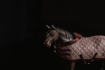 Black toy horse isolated on black background