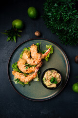 Asian food fried shrimp in almond flakes with lettuce and vegetable dressing on a plate.