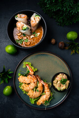 Asian food fried shrimp in almond flakes with lettuce and vegetable dressing with spring rolls with shrimps, cucumbers, rice and cashew nuts with sauce.