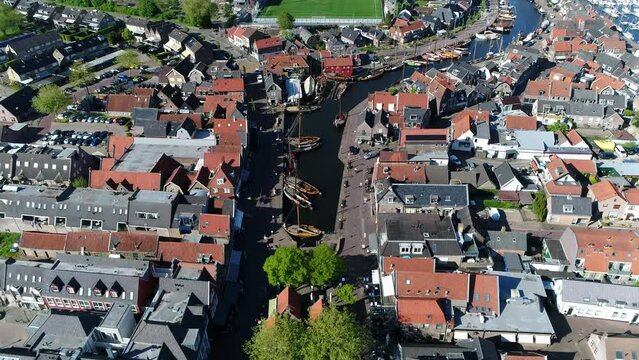 Aerial view of Spakenburg old port showing vintage wooden sailing boats called skutsjes and building left and right of the harbor it used to be a fishing harbour in the past 4k high resolution