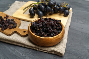 Dried black raisins in wooden spoon with fresh ripe grapes. Healthy snack, dietary product.