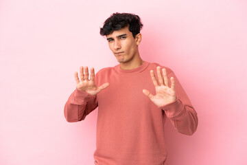 Young Argentinian man isolated on pink background nervous stretching hands to the front