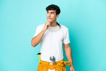 Young electrician Argentinian man isolated on blue background having doubts and thinking