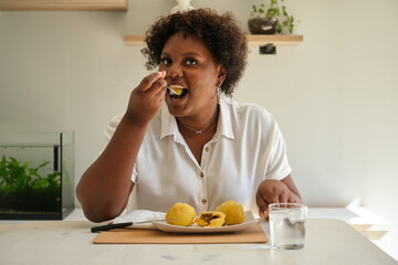 Fototapeta na wymiar Young cuban woman eating homemade cuban style stuffed potatoes and drinking water.