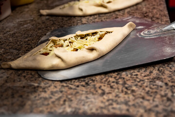 Fototapeta na wymiar chef baker making pide at kitchen. Put on landing shovel and send it to the oven