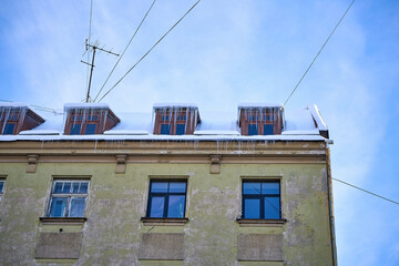 Fototapeta na wymiar Large icicles hanging on the roof of the house in winter time