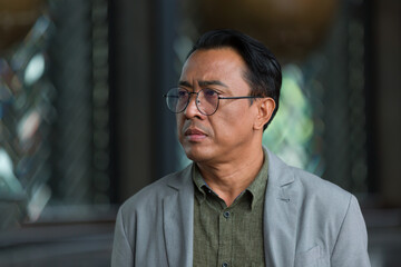 Obraz premium Close up of headshot Asian business man wear glasses and suit standing in the office