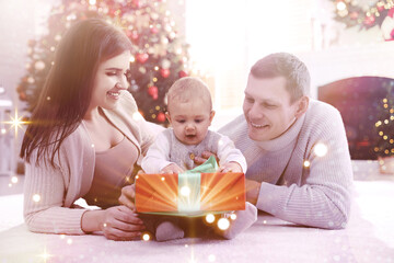 Happy family with cute baby on floor in room decorated for Christmas. Magical festive atmosphere