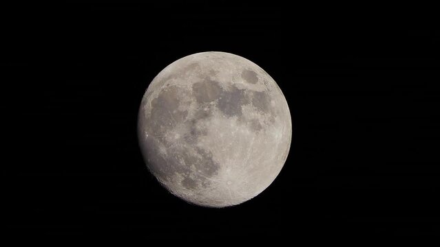 The full Moon moves across the sky at night. Shot through a telephoto lens