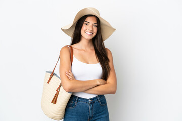 Young Brazilian woman with Pamela holding a beach bag isolated on white background keeping the arms...