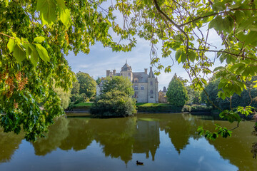 A beautiful shot of a castle unfolding from behind a pond in a park