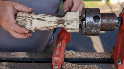 man carving wood on a lathe
