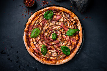 Barbecue pizza with chicken fillet, salami, brisket, barbecue sauce, onion, mushrooms, oregano and basil. Horizontal orientation, top view.