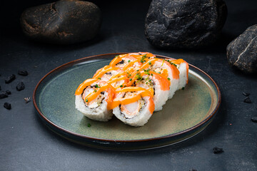 Japanese Philadelphia rolls with shrimp, salmon, avocado, Philadelphia cheese, nori, rice with mango sauce on a plate.