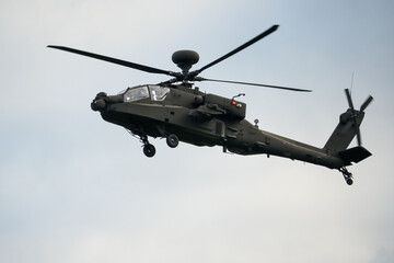 Fototapeta na wymiar close up front quarter view of British army AH-64E Boeing Apache Attack helicopter (ZM722 ArmyAir606) descending to land, autumn sky, Wiltshire UK