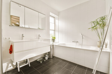 a bathroom with black tile flooring and white tiles on the walls there is a plant next to the...