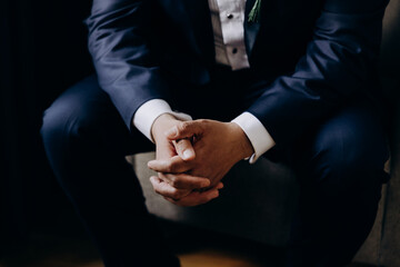 Wedding. A man in a suit and white shirt sits on a chair with his arms folded