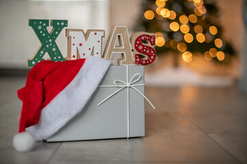 Weihnachtlicher Hintergrund mit Platzhalter. Geschenk vor einen beleuchteten Weihnachtsbaum.
