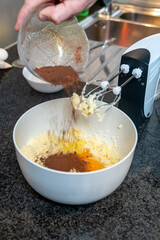 Mixing chocolate with sugar and butter in a white bowl for baking the cake. Blender whisk closeup. Focus selected.